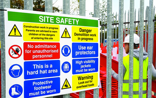 man in construction behind a fence with safety signs